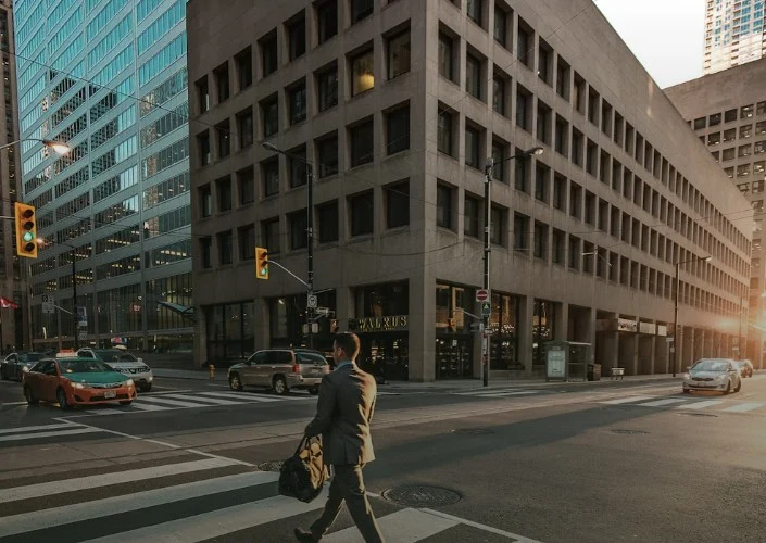A person crossing a downtown street at sunset