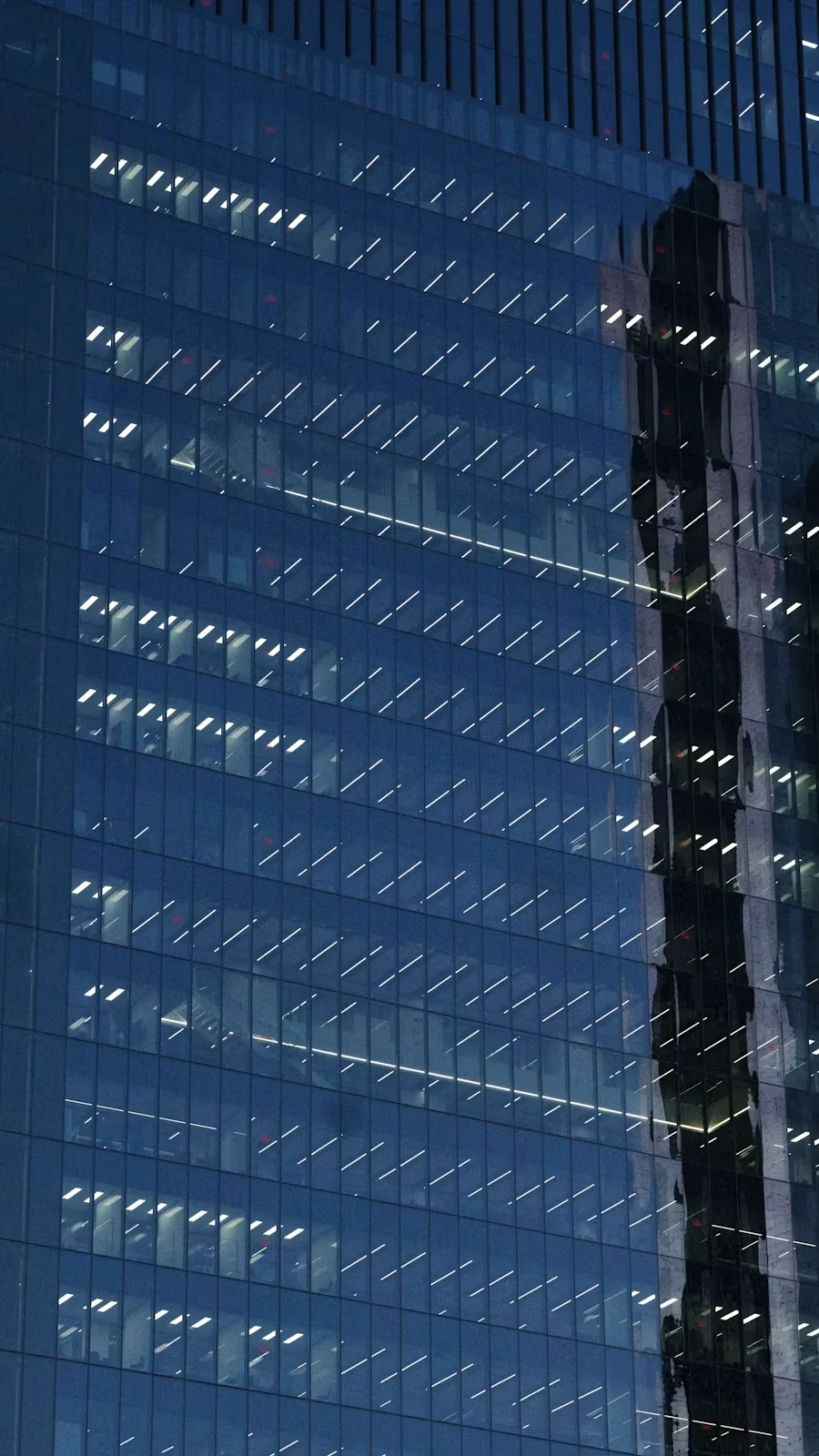 Glass office building with illuminated windows and reflections